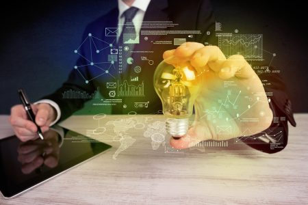 A serious business person has a complex solution concept illustrated by glowing glass light bulb in his hand with graph charts, numbers, lines, calculations.